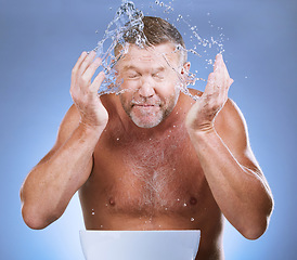 Image showing Man cleaning face, hands and water with hygiene and grooming with clean facial on blue background. Senior male washing skin, basin and beauty with natural cosmetic care, splash and dermatology