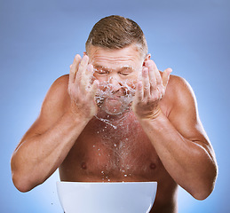 Image showing Man cleaning face, hands and water splash, hygiene and grooming with clean facial on blue background. Senior male washing skin, basin and morning routine with natural cosmetic care and dermatology