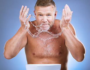 Image showing Man cleaning face, portrait and water splash, hygiene and grooming with clean skincare on blue background. Hands washing skin, basin and mature male with cosmetic care, facial and dermatology