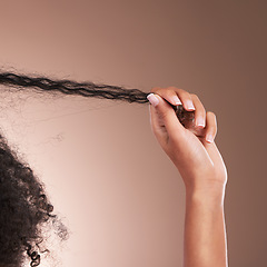 Image showing Hair in hands, afro beauty and black woman on brown background for wellness, shine and natural glow. Salon, luxury treatment and hand with strand for growth with curly hairstyle, texture and care