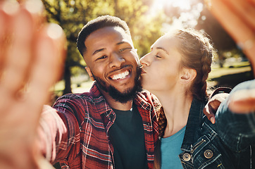 Image showing Interracial couple, selfie kiss and portrait in nature, having fun and bonding together outdoors. Smile, love romance and black man and woman kissing to take photo for happy memory or social media.