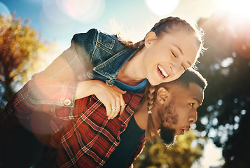 Image showing Interracial couple piggyback in park, summer and outdoor date together in sunshine, happiness and nature. Happy man carrying woman in garden for young love, care and freedom to relax and smile