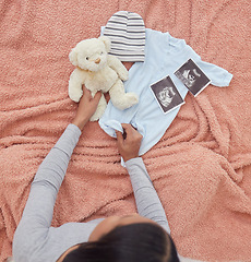 Image showing Baby clothes, scan and pregnant woman preparing for her child or infant in the nursery or bedroom. Pregnancy, love and maternal female looking at a teddy bear, outfit and xray of newborn kid at home.