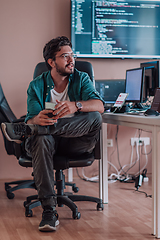 Image showing A programmer diligently testing smartphone applications while sitting in their office.