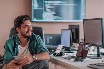 Image showing A programmer diligently testing smartphone applications while sitting in their office.