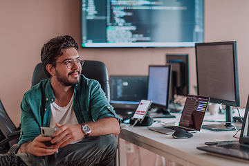 Image showing A programmer diligently testing smartphone applications while sitting in their office.