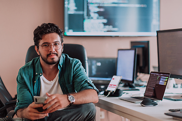 Image showing A programmer diligently testing smartphone applications while sitting in their office.