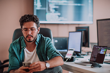 Image showing A programmer diligently testing smartphone applications while sitting in their office.