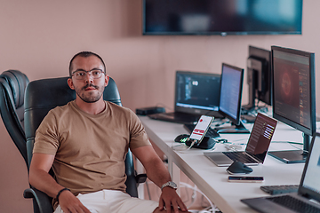 Image showing A programmer diligently testing smartphone applications while sitting in their office.