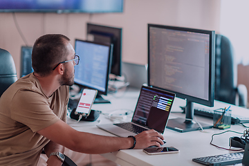 Image showing A programmer diligently testing smartphone applications while sitting in their office.