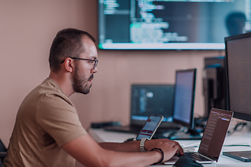 Image showing A programmer diligently testing smartphone applications while sitting in their office.