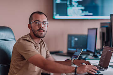 Image showing A programmer diligently testing smartphone applications while sitting in their office.