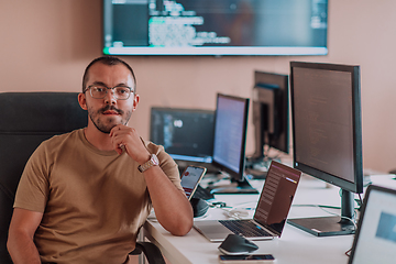 Image showing A programmer diligently testing smartphone applications while sitting in their office.