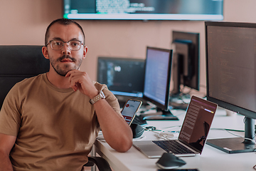 Image showing A programmer diligently testing smartphone applications while sitting in their office.