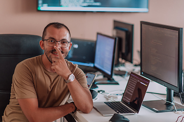 Image showing A programmer diligently testing smartphone applications while sitting in their office.