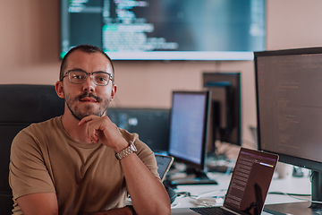 Image showing A programmer diligently testing smartphone applications while sitting in their office.