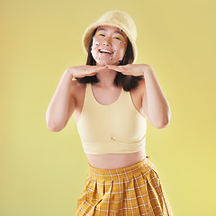 Image showing Fashion, hands on face and portrait of woman with comic eyes isolated on yellow background. Happy, funny and asian girl with a smile for gen z beauty and creativity with color clothes in studio