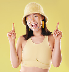 Image showing Portrait, pointing and woman with eyes for comedy isolated on yellow background in a studio. Direction, comic and Asian girl with gesture up and facial product for expression and funny on a backdrop