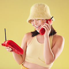 Image showing Woman, landline phone call and studio background for yellow fashion, excited and smile with eyes sticker art on face. Asian gen z model, 90s aesthetic and telephone communication, talk or happy chat