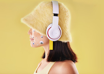 Image showing Eye stickers, music headphones and woman in studio isolated on a yellow background mockup. Funny, technology and face profile of female listening, enjoying and streaming radio, podcast and audio.