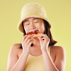 Image showing Asian girl, eating pizza and studio with fashion, happiness and retro 90s aesthetic by yellow background. Young gen z model, junk food and happy with meal, cheat snack and beauty with facial makeup