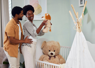 Image showing Love, pregnancy and couple with teddy bear in the nursery with excitement while preparing for their baby. Happy, smile and young African man with his pregnant wife looking at toy together in bedroom.