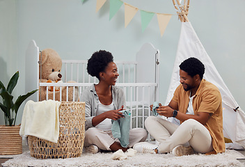 Image showing Pregnant and baby room and black couple happy to prepare for a family home and folding clothes. Man and woman together talking about excited pregnancy future, love and life insurance on bedroom floor