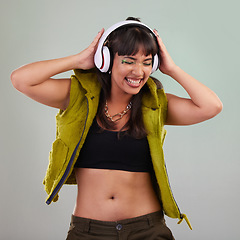 Image showing Music, dance and woman with headphones in studio, happy and excited isolated on grey background. Streaming service, song and gen z fashion, girl dancing with hands up and smile to online radio dj.