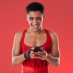 Image showing Fashion, phone and gay man on social media in studio on a red background for communication. Mobile, transgender and a happy lgbt person looking at an internet meme while fashionable on a backdrop