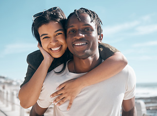 Image showing Happy couple, portrait and piggyback by beach in relax romance holiday, love vacation date or summer travel location. Smile, bonding and man carrying black woman in fun game, freedom trust or support