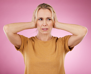 Image showing Loud, studio and woman closing her ears in a studio for noise distraction, sound or complaint. Upset, mad and annoyed female model with a hands on her head for cover isolated by a pink background.