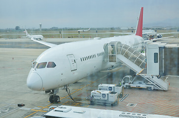 Image showing Airplane, airport or loading luggage on runway for traveling outdoors at worldwide location for journey. Trip, transportation services or commercial aeroplane on ground for international flight cargo