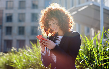 Image showing Business woman, phone and smile for communication, social media or texting and chatting in city. Happy female ginger typing and smiling on smartphone for 5G connection, mobile app or networking