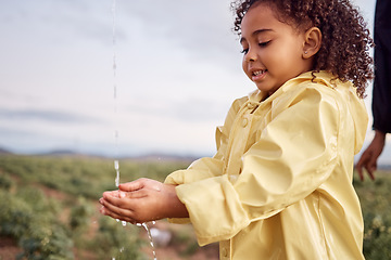 Image showing Kid, child and young girl washing hands for hygiene and sustainability in nature on a farm in winter. Water and splash outdoor by rinsing and cleaning hand for eco friendly or natural sanitation