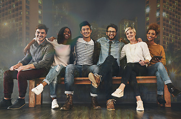 Image showing Diversity, friendship and portrait of people with a city background sitting together. Happy, smile and multiracial young friends hugging or embracing on a bench with support, unity and community.