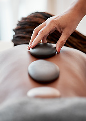 Image showing Black woman, hands and rock on back in spa treatment for relaxation, stress relief or massage at resort. Hand of masseuse applying rocks to African American female in physical therapy for wellness