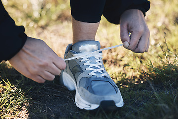 Image showing Closeup, shoes ad man runner in a park for training, sports or morning cardio preparation. Hand, sneaker and athletic guy with lacec before run in field, exercise or marathon practice workout outdoor