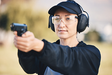 Image showing Woman, gun and learning to shoot weapon at shooting range outdoor for security, training and target. Person with safety headphones and glasses for sport, competition or safety with gear in hands