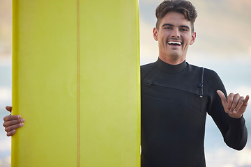 Image showing Hand sign, portrait and surfer with smile, fitness and training for wellness, balance and healthy lifestyle. Face, guy and male athlete with surfboard, freedom and happiness for adventure or vacation