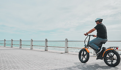Image showing Ebike, mockup and travel with a senior man on the promenade, riding eco friendly transport by the beach. Sustainability, cycling and mock up with a mature male tourist by the seaside for a ride
