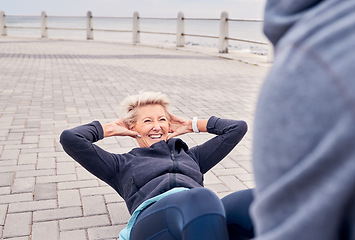 Image showing Senior woman, fitness and sit ups with personal trainer at the beach for strong ab workout or exercise. Happy elderly female smile for core, stomach or abdomen training with health coach by the sea