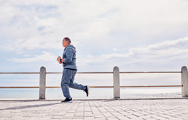Image showing Senior man, sports and running at beach promenade with sky mockup for energy, body wellness and cardio workout. Elderly male, exercise and runner at seaside for training, fitness and healthy marathon