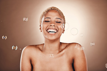 Image showing Cosmetics, black woman and skincare with bubbles, laughing and brown studio background. African American female, lady and beauty with dermatology, aesthetic and wellness with soap bubble or soft skin