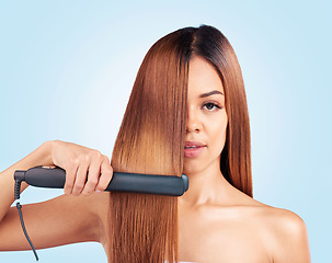Image showing Face portrait, beauty and woman with hair straightener in studio isolated on a blue background. Haircare, product and female model with flat iron for salon treatment, hairstyle aesthetic or balayage.