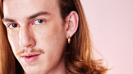 Image showing Face portrait, beauty and man with makeup in studio isolated on a pink background. Gen z, lgbtq and gay, queer or homosexual young male model with gold glitter cosmetics for aesthetics and skincare.