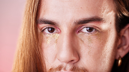 Image showing Makeup, eyes and portrait of gen z man with serious expression on face with pink background. Gold, glitter tears and art, zoom on eye cosmetics on non binary, transgender or gender neutral lgbt model
