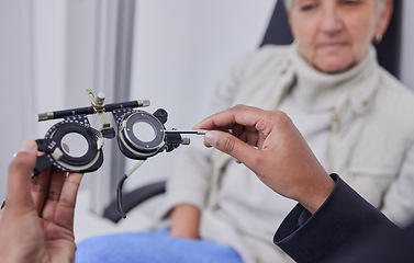 Image showing Optometrist hands, test glasses and senior woman for health advice and helping hand in consultation room. Elderly patient, healthcare or doctor for eyes, reading or eyesight in retirement at clinic