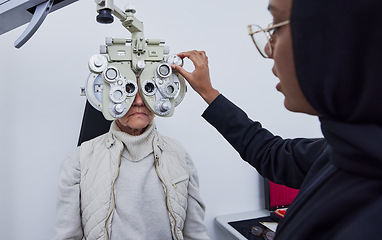 Image showing Eye exam, vision and woman with Muslim optometrist in clinic for test, eyesight and optical assessment. Optometry, healthcare and optician with elderly patient on phoropter, lens and medical machine