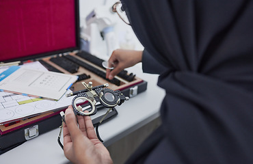 Image showing Hands, vision and optometry with an islamic woman at work in eyecare for prescription lenses for sight correction. Doctor, medical or glasses and a muslim female optician working with eyewear