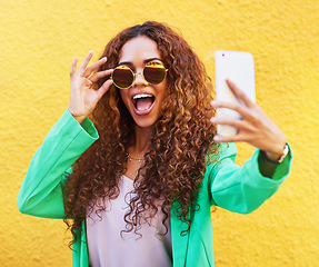 Image showing Selfie, fashion and woman with sunglasses on yellow background, color wall and gen z backdrop. Happy young female, trendy style and take profile picture on social media, green clothes and curly hair